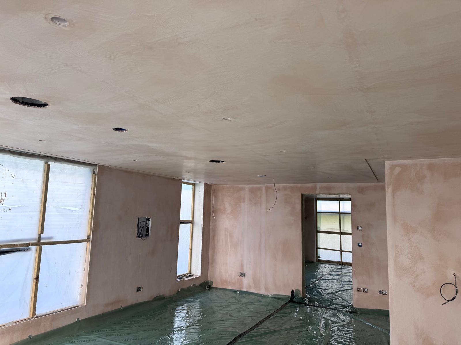 Fresh plaster finish across internal walls and ceiling, with floors protected during the work