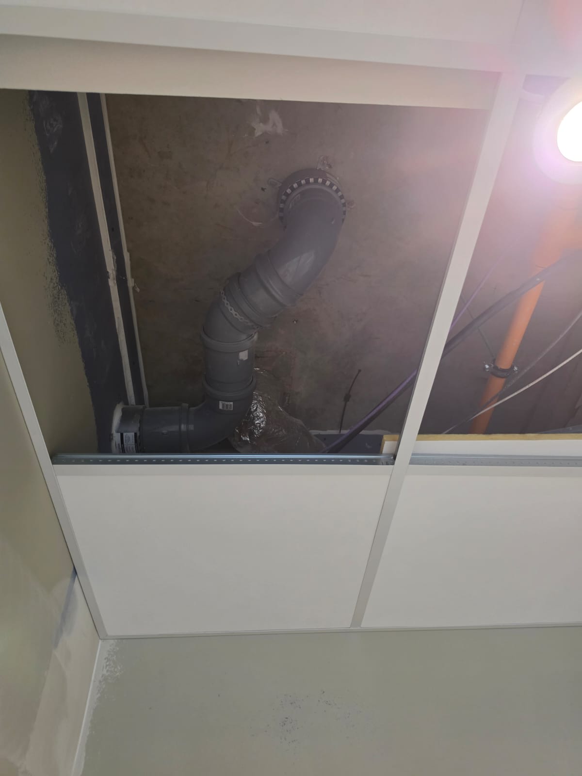 White lay-in ceiling tiles and exposed suspended grid with an open service void