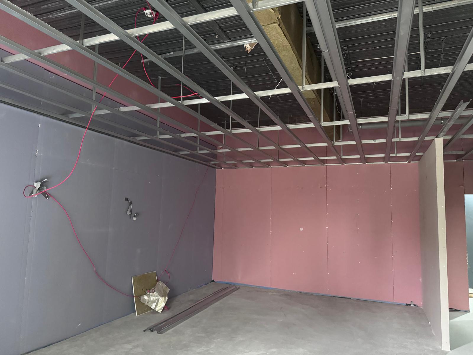 Suspended metal ceiling framework above boarded walls