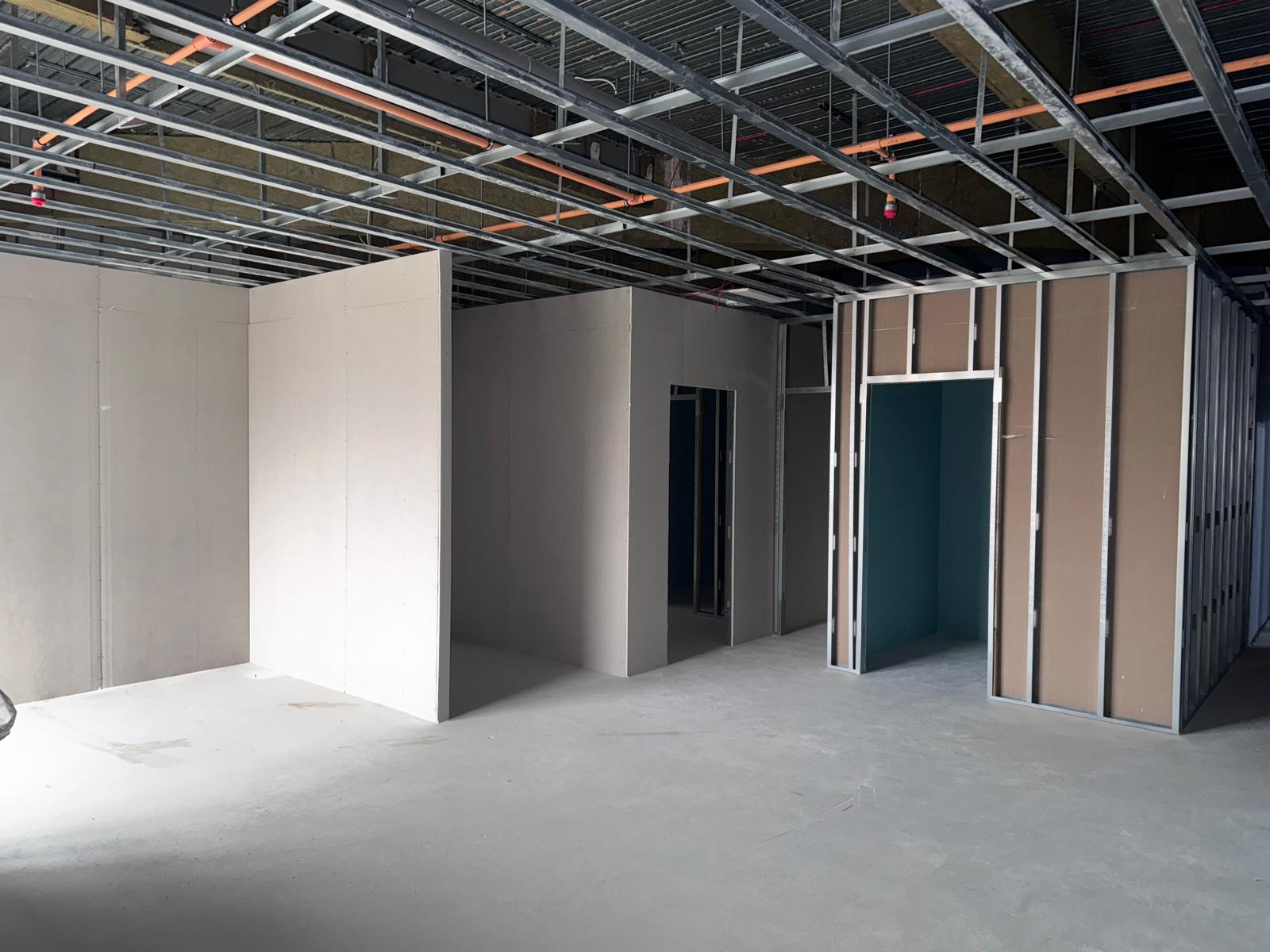 Partially boarded partitions beneath an exposed metal ceiling framework