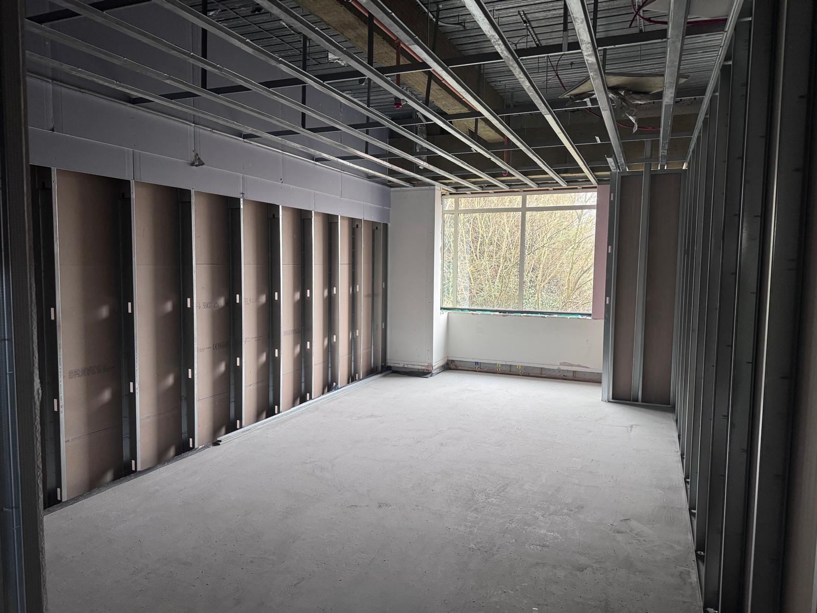 Room with exposed metal stud wall framing and suspended ceiling channels